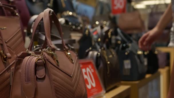 Ung kvinna väljer syntetisk läder påse i Modekläder och accessoarer butik. Kund Girl köpa handväska till försäljning i köpcentrum. Rabatt koncept. 4K — Stockvideo