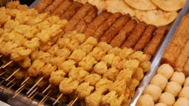Derin kızarmış et topları bir sürü ve sopa üzerinde Satay. Asya sokak yemekleri. Barbekü, çubuklarla ızgara. Asya ülkelerinde Fast Food. Akşam sokak pazarında geleneksel Asya yemekleri. 4k