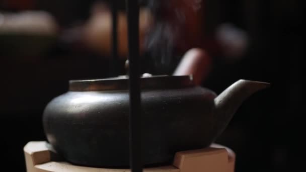 Bule de metal chinês tradicional em um fogão de barro ferve a água para a cerimônia do chá. Fecha a porta. 4k — Vídeo de Stock