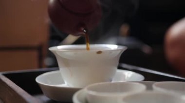 Geleneksel Çin gongfu veya kung fu çay töreni. Çay ustası gaiwan veya zhong içine fermente yeşil çay döker. Geleneksel Çin kültürünün unsuru. Closeup. 4k