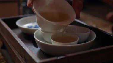 Çay ustası gaiwan veya zhong için çay bardakiçine yeşil çay döker. Geleneksel Çin gongfu veya kung fu çay töreni. Geleneksel Çin kültürünün unsuru. Closeup. 4k