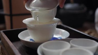 Geleneksel Çin gongfu veya kung fu çay töreni. Çay ustası gaiwan veya zhong içine yeşil çay döker. Geleneksel Çin kültürünün unsuru. Closeup. 4k
