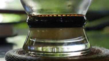 Kafede Vietnam geleneksel phin filtre kullanarak süt ile kahve demleme. Kahve damlaları yavaşça cam bir bardağa damlar. Ca phe sua da. Closeup. 4k