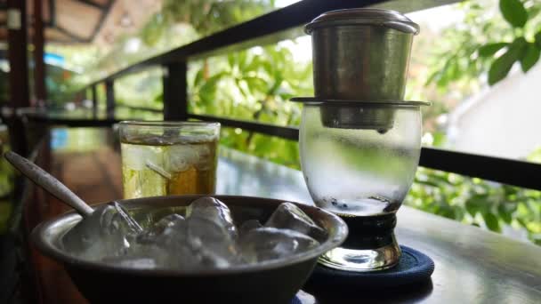 Bryggning av svart kaffe med ett vietnamesiskt traditionellt Phin filter i kaféet. Kaffet droppar långsamt i en Glaskopp. Ca Phe den da. Närbild. 4K — Stockvideo