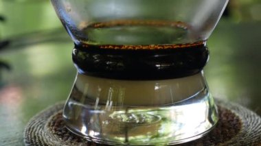 Kafede Vietnam geleneksel phin filtre kullanarak süt ile kahve demleme. Kahve damlaları yavaşça cam bir bardağa damlar. Ca phe sua da. Closeup. 4k