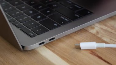 Klavyede erkek el yazma ve beyaz güç Usb-C veya Type C Kablosu nu dizüstü bilgisayarlara takmak Usb-C bağlantı noktasını bilgisayarlar. Yıldırım konektörü. Closeup. 4k