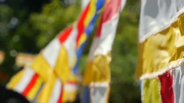 Buddhist prayer flags swaying in the wind in the rays of the rising sun in a temple. Closeup Slow Motion Footage. Shallow depth of field — Stock Video