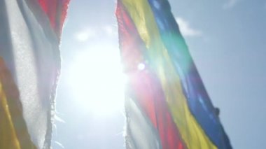 Budist dua bayrakları bir tapınakta yükselen güneşin ışınları rüzgarda sallanan. Closeup Yavaş Çekim Görüntüleri. Sığ alan derinliği