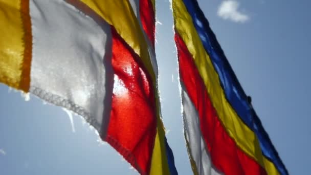Buddhista ima zászlók imbolygott a szél a sugarait a felkelő nap egy templomban. Closeup lassú Motion Footage. Sekély mélységélesség — Stock videók
