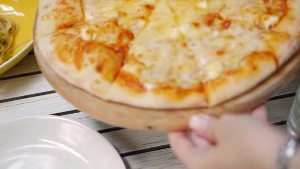 Τα χέρια του σερβιτόρου βάζουν έτοιμη νόστιμη πίτσα στο τραπέζι στο εστιατόριο. Closeup — Αρχείο Βίντεο