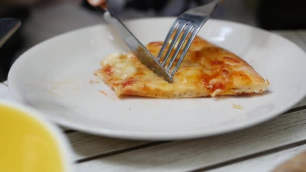 Woman cuts a piece of pizza with a knife and fork. Delicious food for gluttony and enjoyment. Fast food eating concept. Slow motion. Closeup — Stock Video