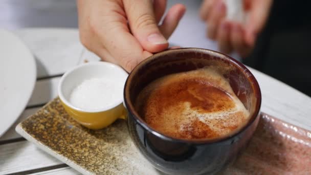 Ženská ruka si vezme šálek cappuccino se Skopový v kavárně. Přestávka na kávu. Detailní