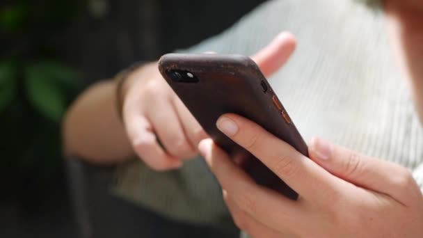 Närbild av handen på en kvinna med hjälp av smartphone när du sitter i kaféet. Girl använder mobilappar. — Stockvideo