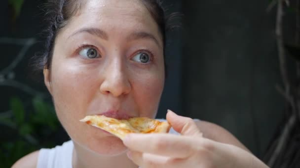 Mujer triste pensativa comiendo una rebanada de pizza en el café. Disfrutando el sabor. Primer plano. — Vídeo de stock