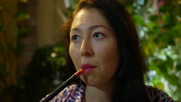 Belle, jeune femme fumant narguilé au restaurant. Fille attrayante fumant du tabac aromatisé. Éteignez la fumée. 4k — Video