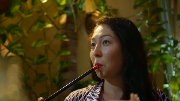 Krásná mladá žena kouřící vodní dýmka v restauraci. Atraktivní dívka kouřící tabák s příchutí. Sfoukni kouř. 4k — Stock video