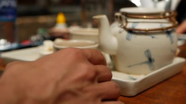 Молодая женщина пьет красный чай из маленькой миски, сидя в кафе — стоковое видео