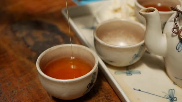 Pouring honey into small bowl with red tea on a wooden table at cafe — Stock Video