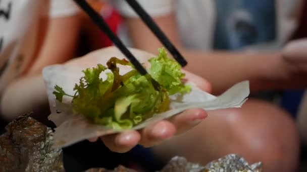 Touristen bereiten Frühlingsrollen mit Reispapierwickel oder Banh Trang auf dem nächtlichen Streetfood-Markt zu und essen sie. traditionelle vietnamesische nem Gericht, asiatische Küche. Nahaufnahme — Stockvideo
