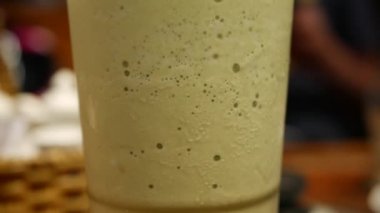 Bir bardak matcha buzlu çayda hava kabarcıkları yükselir. Close