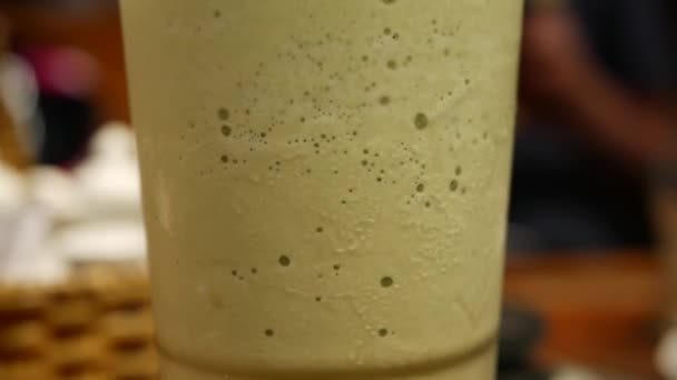 Пузырьки воздуха поднимаются в стакан чая со льдом маття. Крупный план — стоковое видео