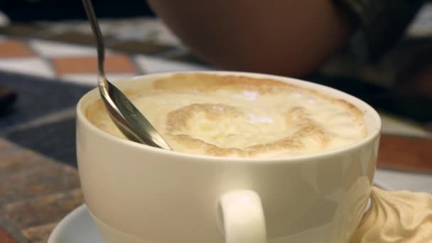 Meisje probeert slagroom schuim in haar koffie. Koffiepauze. Close-up — Stockvideo