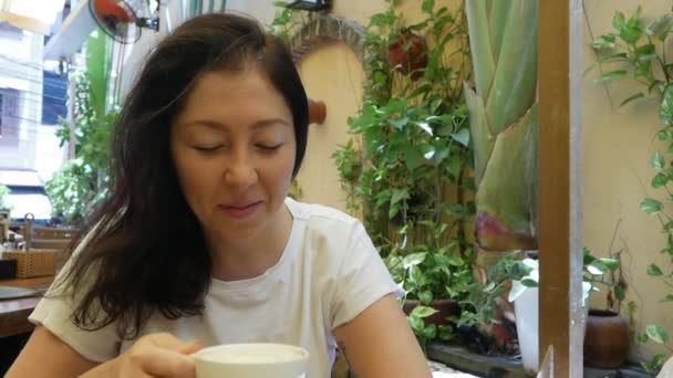 Hermosa joven feliz bebe café en la cafetería por la mañana. modelo femenino disfrutando de café expreso o té . — Vídeos de Stock