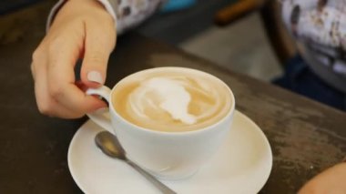 Kadın eli kafede bir fincan Cappuccino içer. Kahve molası. Yakın çekim.