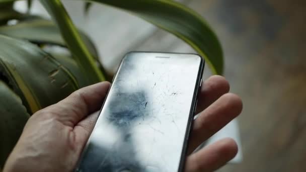 Concepto de teléfono inteligente con pantalla rota. Vista superior de las manos del hombre sosteniendo un teléfono con pantalla agrietada. Tacto lcd agrietado, destrozado. Pantalla en el teléfono celular moderno — Vídeo de stock