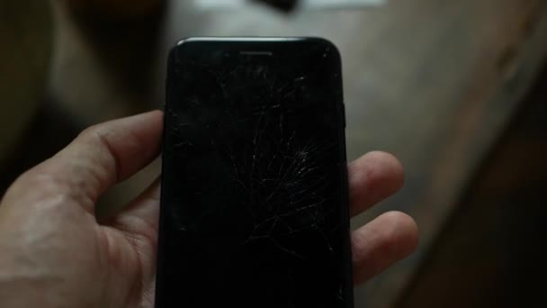 Concepto de teléfono inteligente con pantalla rota. Vista superior de las manos del hombre sosteniendo un teléfono con pantalla agrietada. Tacto lcd agrietado, destrozado. Pantalla en el teléfono celular moderno — Vídeo de stock