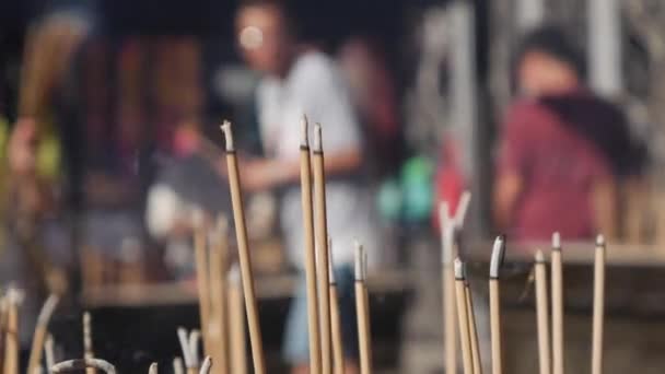 Les gens qui prient et adorent dans le temple taoïste s'inclinent et tiennent des bâtons d'encens pendant la célébration du Nouvel An chinois. Le grand pot extérieur avec des encens, rempli de sable, est — Video