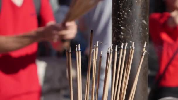 Människor ber och dyrkar i Taoist tempel interiör buga och hålla rökelse pinnar under firandet av kinesiska nyår. Den stora utomhus potten med rökelser, uppfylld med sand, är — Stockvideo