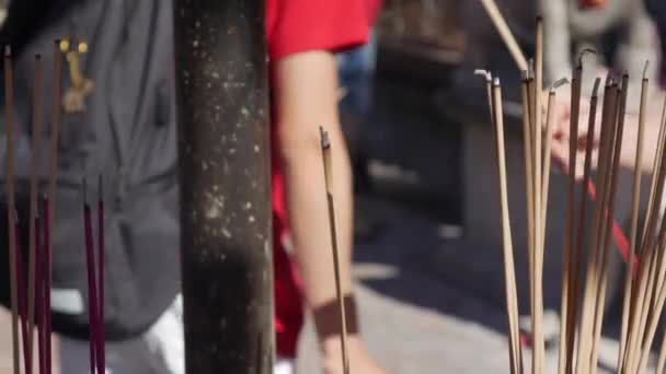 Pessoas orando e adorando no interior do templo taoísta curvando e segurando paus de incenso durante a celebração do Ano Novo Chinês. O grande pote ao ar livre com incensos, preenchido com areia, é — Vídeo de Stock