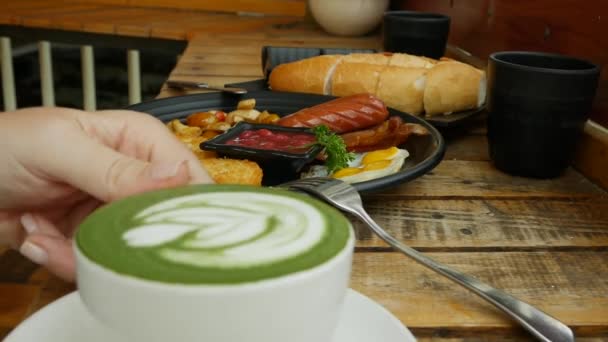 Dziewczyna Bierze Filiżankę Matcha Latte Drewnianego Stołu Restauracji — Wideo stockowe