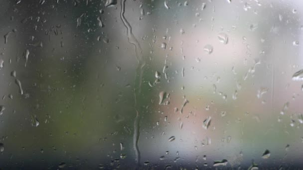 El agua de lluvia fuerte se descarga contra el vidrio de la ventana y fluye hacia abajo. Primer plano. Gotas de lluvia sobre fondo de vidrio en temporada de lluvias — Vídeo de stock