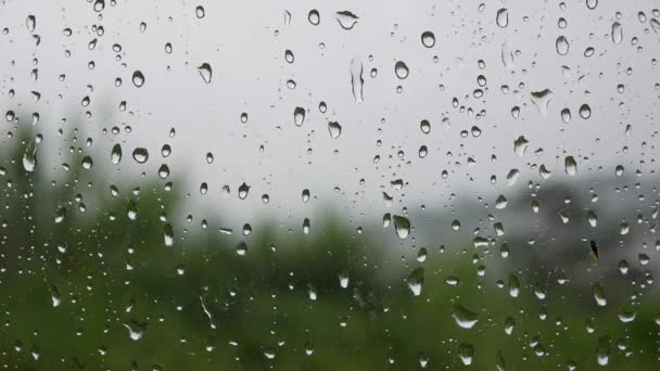 El agua de lluvia fuerte se descarga contra el vidrio de la ventana y fluye hacia abajo. Primer plano. Gotas de lluvia sobre fondo de vidrio en temporada de lluvias — Vídeos de Stock