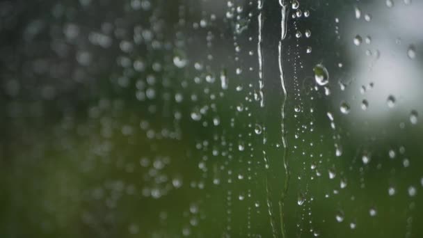 Silná dešťová voda se spláchne na okenní sklo a stéká dolů. Detailní záběr. Dešťové kapky na skleněném pozadí v období dešťů — Stock video