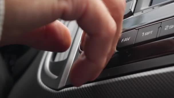 Main d'homme avec une bague de mariage tournant le volume de la radio à l'intérieur de la voiture le jour du voyage dans la grande ville à l'écoute de la musique sur l'autoroute. Réglage du volume sur le système audio de la voiture. Gros plan — Video