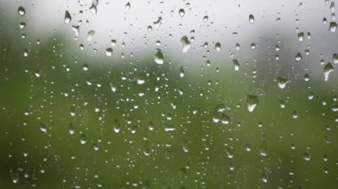 Şiddetli yağmur suyu pencere camlarına ve akıntıya karşı akar. Yakın plan. Yağmur mevsiminde cam zemin üzerinde yağmur damlaları
