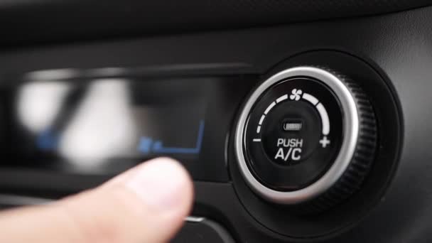 Κοντινό πλάνο του πατώντας ένα κουμπί για να ενεργοποιήσετε το κλιματιστικό σε ένα αυτοκίνητο. Το αντρικό χέρι γυρίζει το κουμπί. — Αρχείο Βίντεο