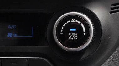 Bir arabanın klimasını kapatmak için bir düğmeye basmaya yakın çekim. Erkek eli düğmeyi çevirir.