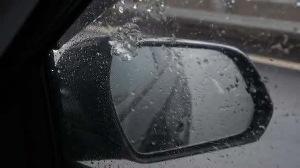 View out the rear view mirror as car drives on highway in the rain — Stock Video