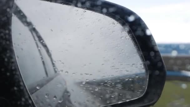 View out the rear view mirror as car drives on highway in the rain — Stock Video