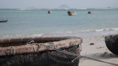 Geleneksel Vietnamlı yuvarlak teknesi deniz arka planındaki balıkçı köyünde kumlu sahilde. Balıkçı gemisi ve kültür sembolü