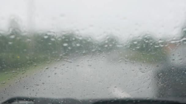 Limpiaparabrisas limpiar el parabrisas del coche sobre la marcha durante las fuertes lluvias. Vista interior borrosa de un camino rural. Conducir en condiciones climáticas difíciles — Vídeos de Stock