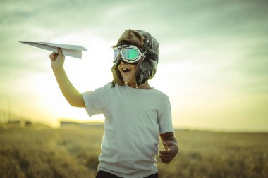 boy at sunset playing at being aviator, he wears pilot glasses of airplanes and some cardboard like wings clipart