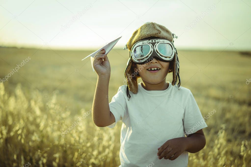 boy at sunset playing at being aviator, he wears pilot glasses of airplanes and some cardboard like wings