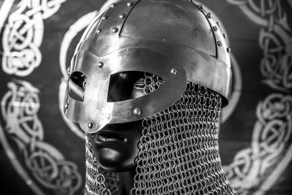 viking warrior helmet with chainmail over shield with drawings and viking symbolism, traditional art of northern europe