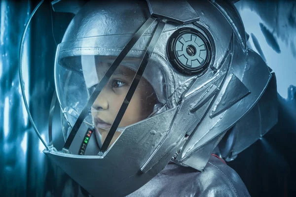 Future, Boy playing to be an astronaut with space helmet and metal suit over silver background