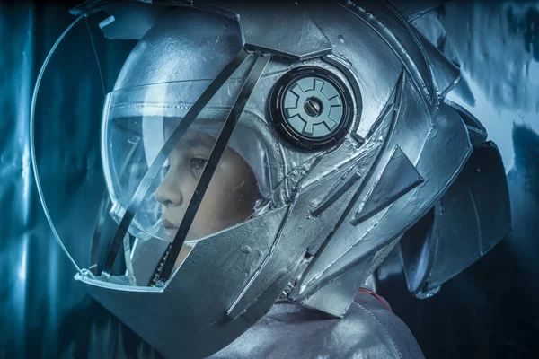 男孩扮演一个宇航员的空间头盔和银色西装的金属背景 — 图库照片